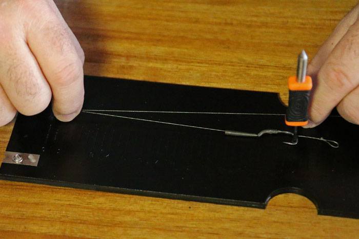 16. Breng nu het onderlijnmateriaal tussen het tooltje en het pennetje van de Rigruler onder spanning.