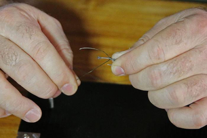 5 Laat een klein stukje voorbij je haakoog steken. Pak de lus en draai 1x om de haaksteel. Daarna kruislings terugwikkelen naar je vinger. Doe dit 3x. Aantrekken bij stuk onderlijn bij je haakoog